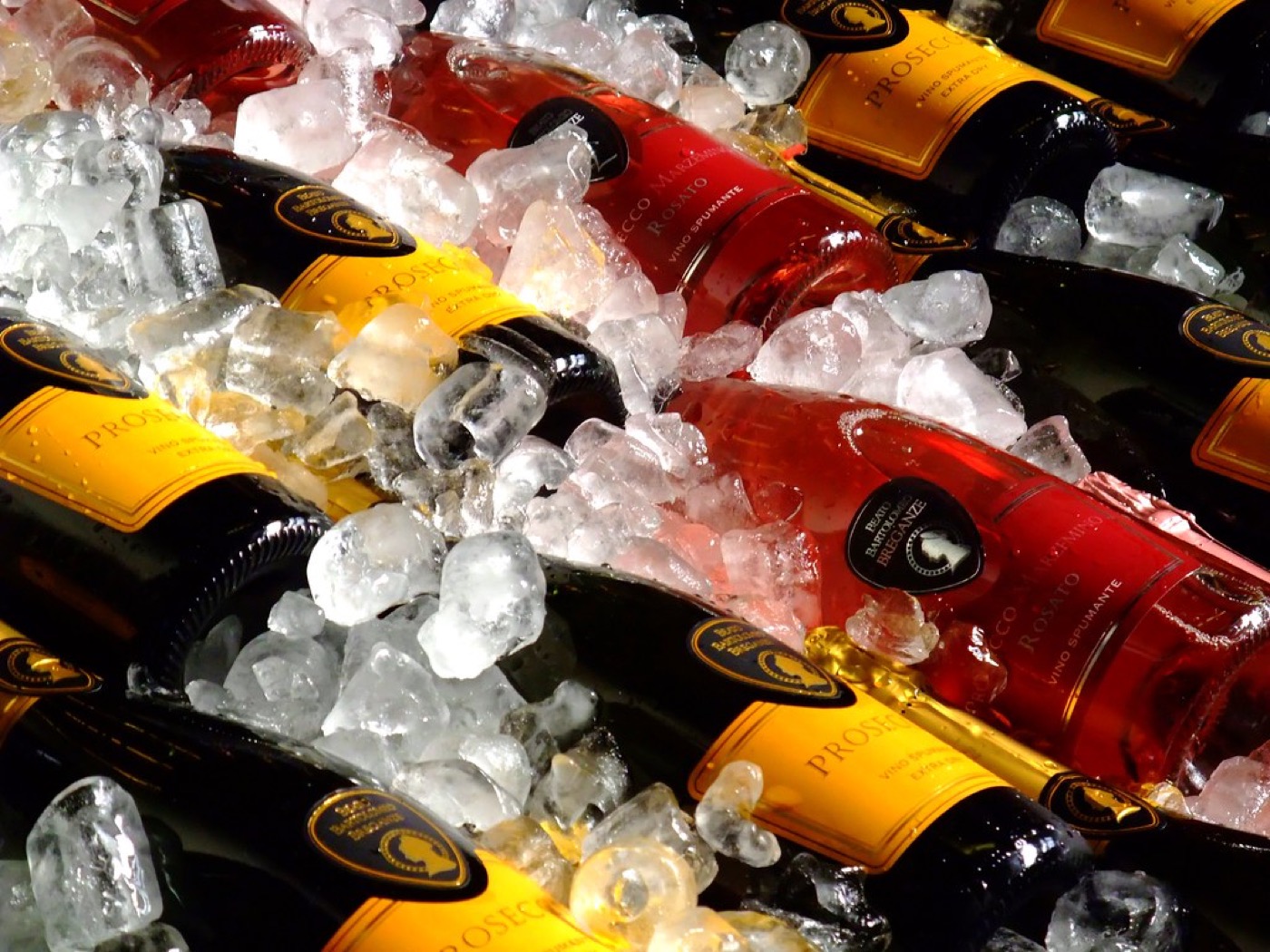 Mehrere Prosecco-Flaschen liegen in zerstoßenem Eis