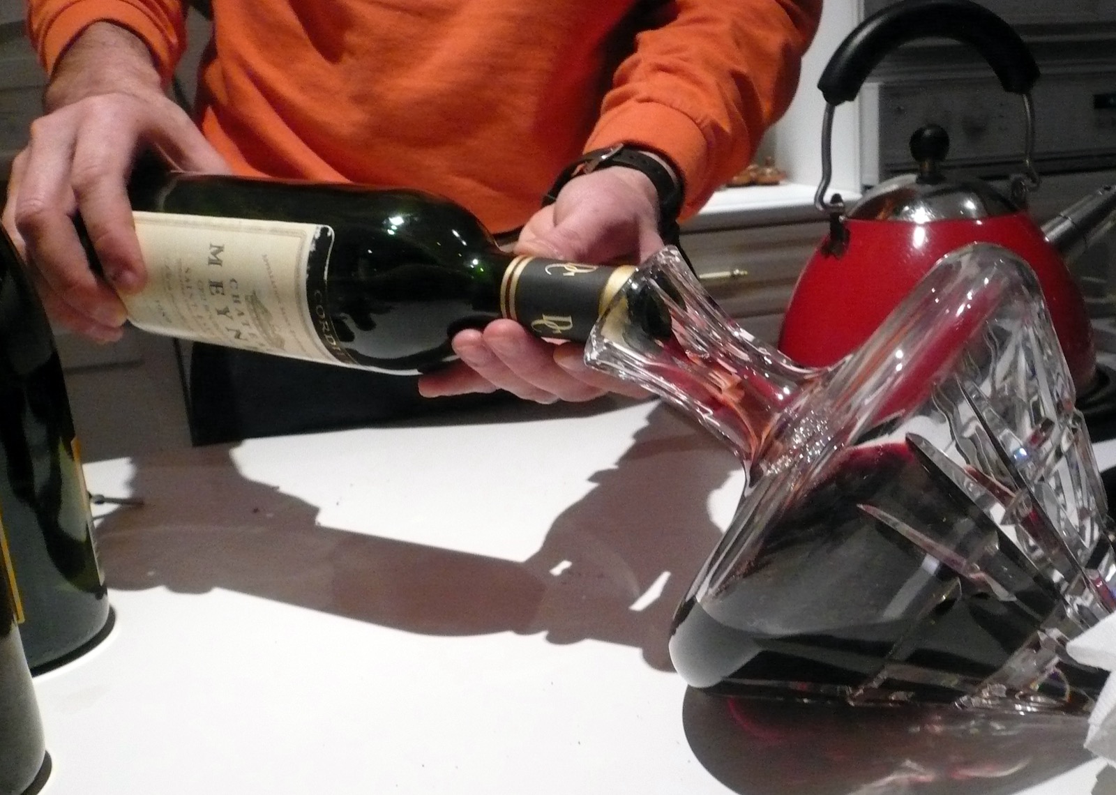 Rotwein wird aus der Flasche langsam in einen Kristall-Dekanter umgefüllt